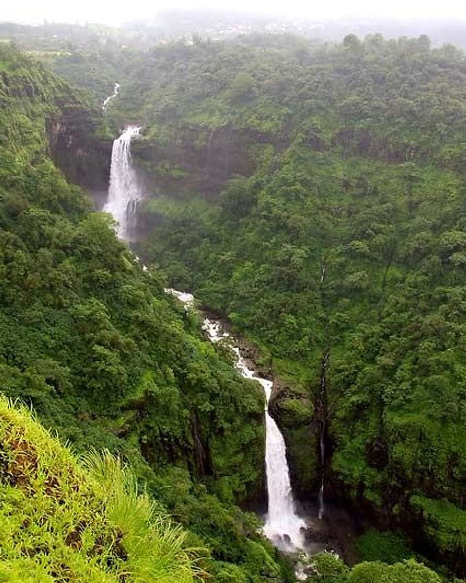 A tall waterfall dropping through green Sahyadri hills in the monsoon